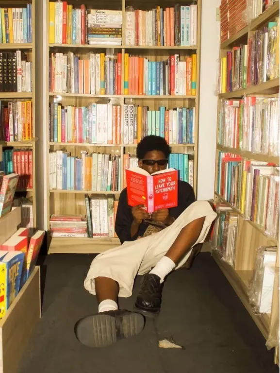 Persona leyendo un libro sentada en el suelo de una librería